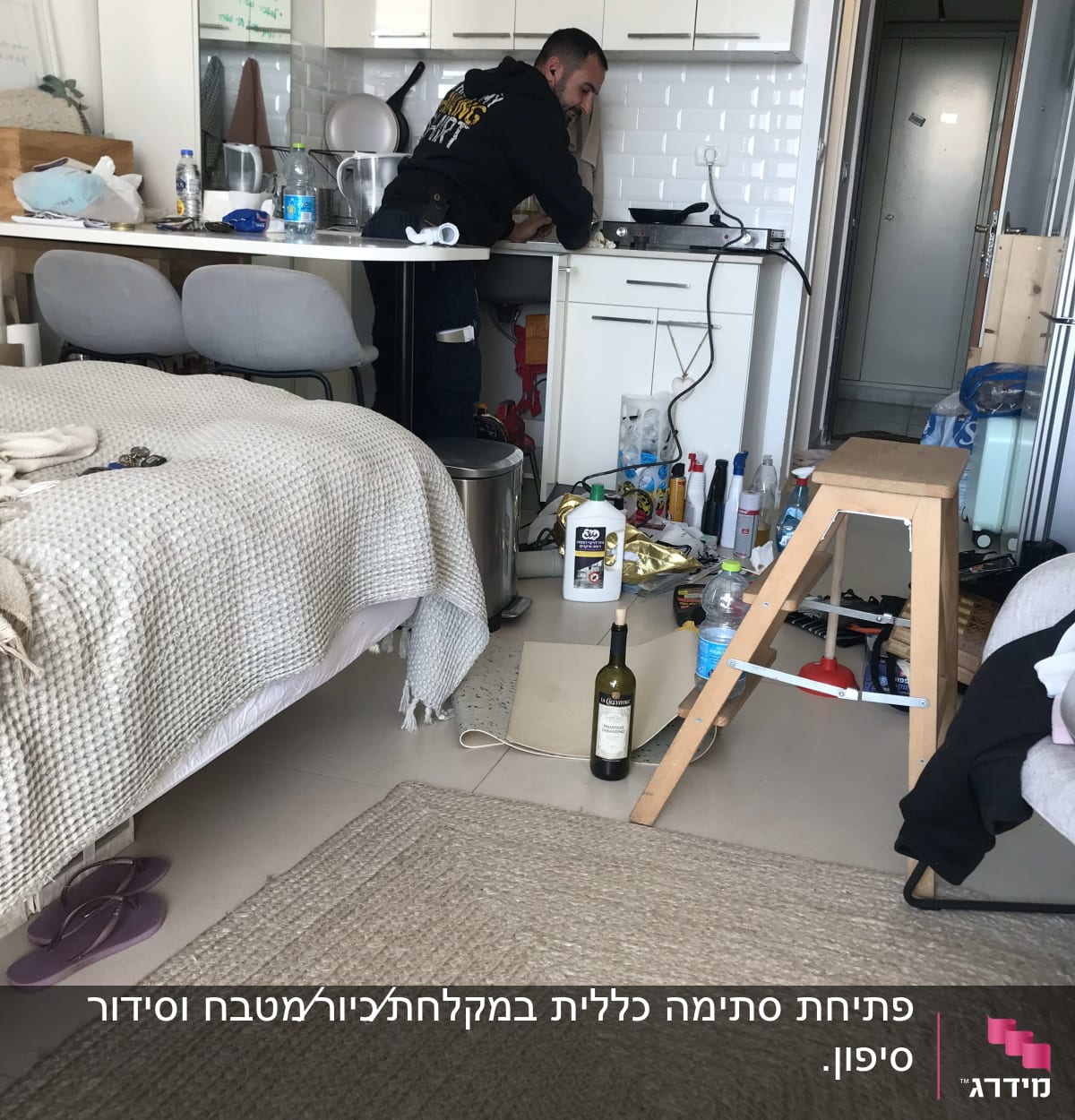 אדם עובד מתחת לכיור במטבח עם כלים